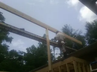 Carpenter setting a ridge beam over a new addition frame — Ice Dam Removal by Roofing Brothers in Spring City