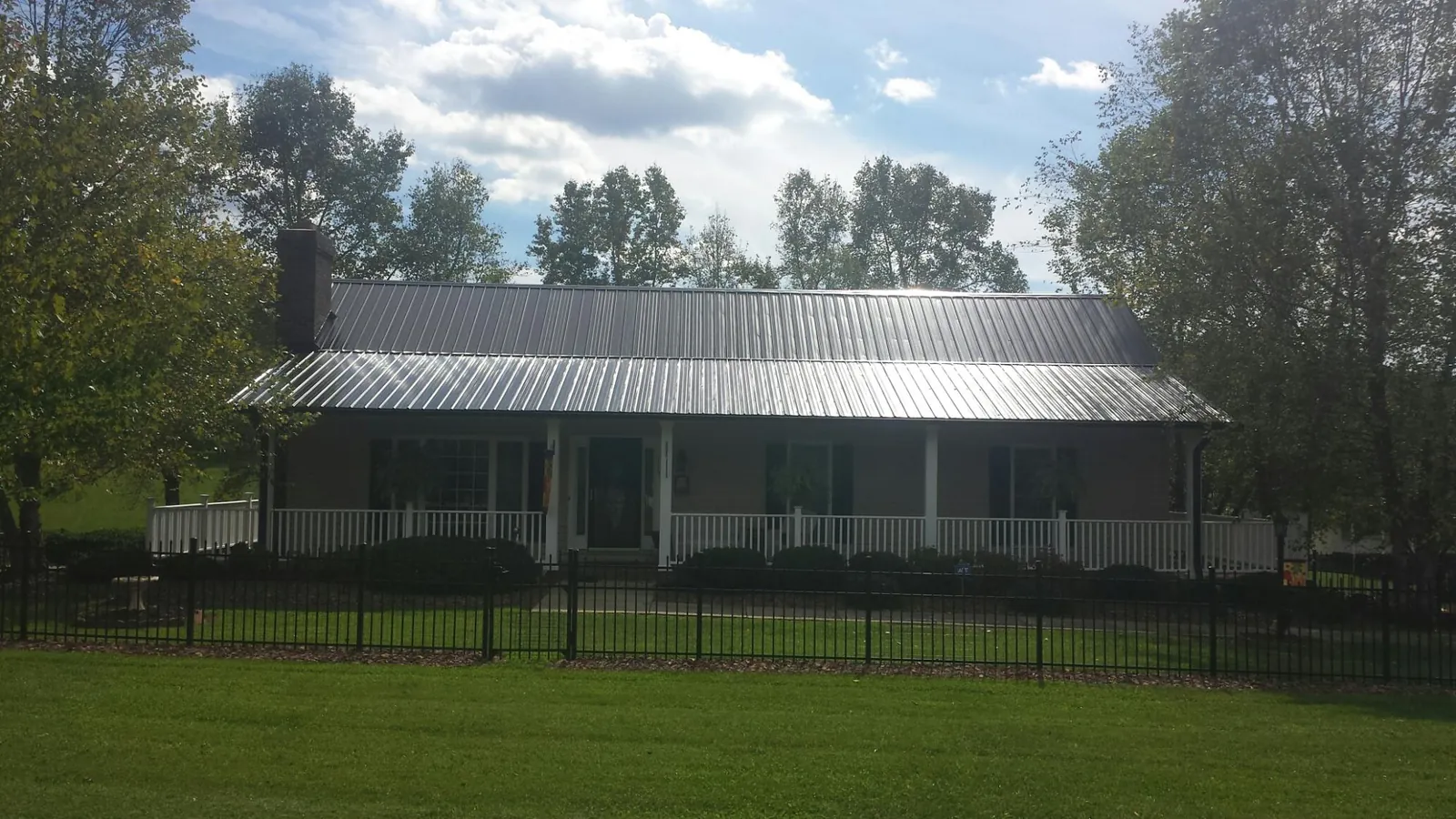 Gray metal roof on a brick ranch with a full width front porch — Gutter Guard Installation work by our crew in Spring City