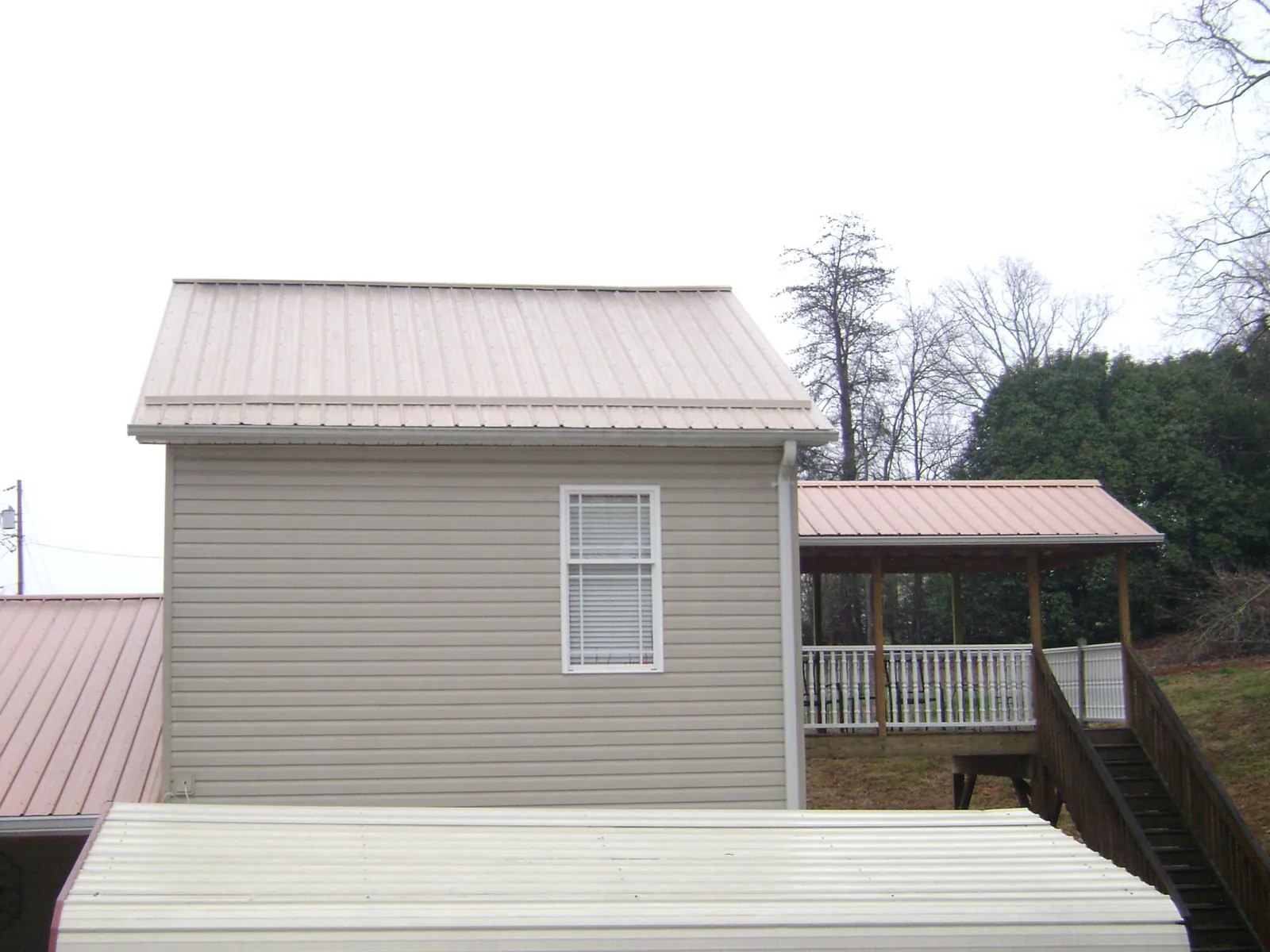 Tan metal roofs on a two story addition and attached porch, from a Roof Replacement job in Spring City